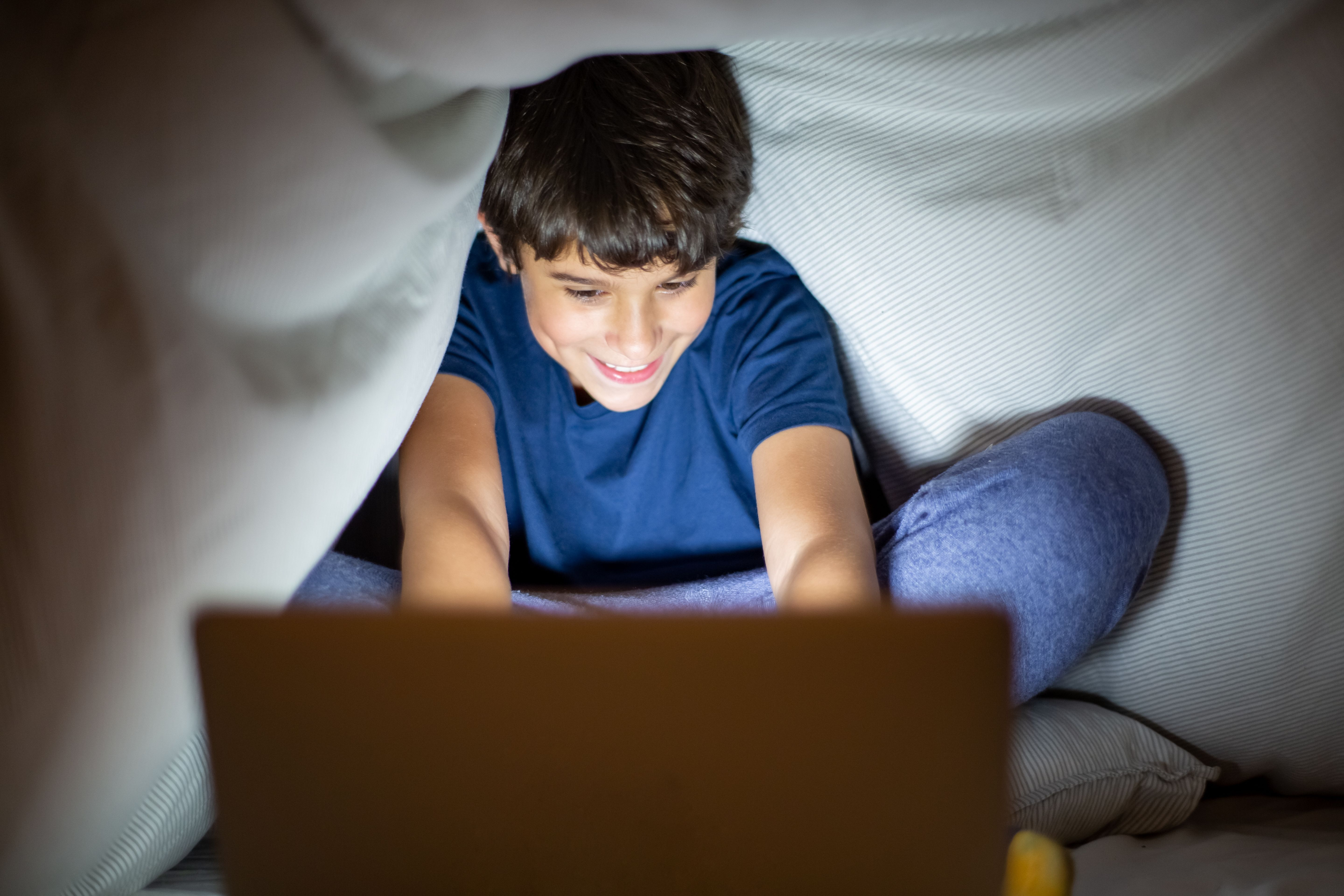 A child using a laptop in bed at night